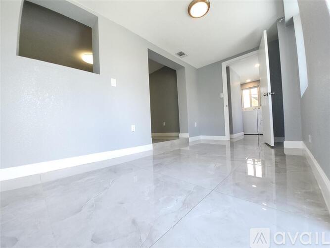 A spacious room with marble flooring and a doorway leading to another room.