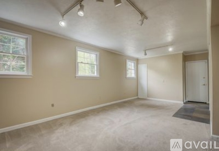 A spacious room with a door, a window, and a ceiling light.