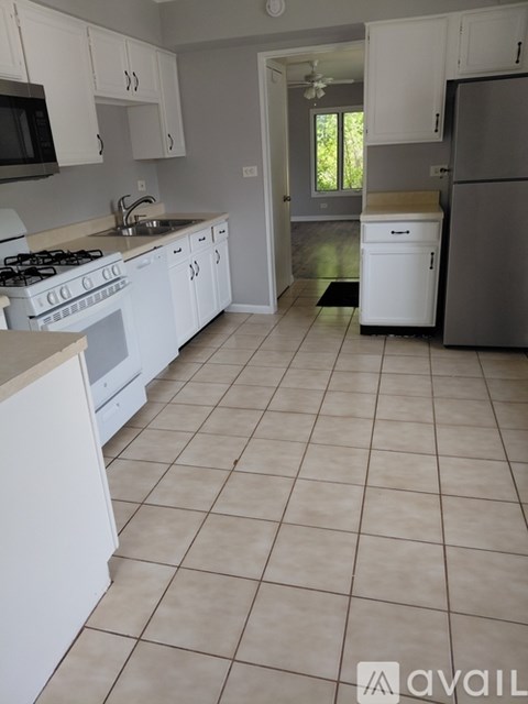A kitchen with white cabinets and a tiled floor.
