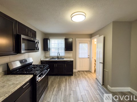 A kitchen with black cabinets and a stove top oven.