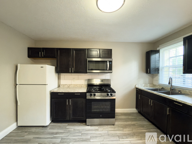A kitchen with black cabinets and a white refrigerator.