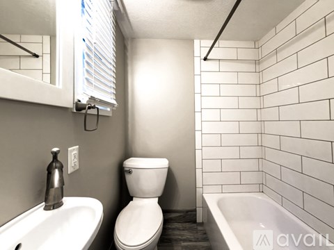 A white toilet sits next to a sink in a bathroom with white tiles.
