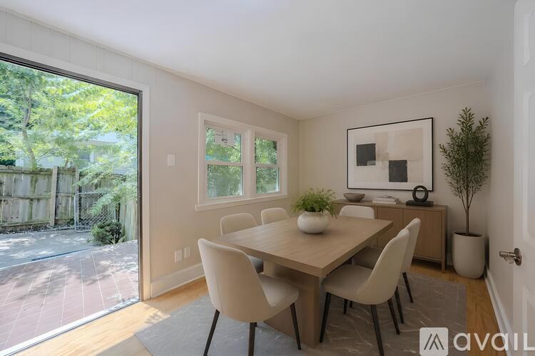A dining room with a table and chairs and a plant on the side table.