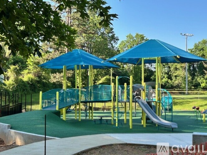 A playground with a blue umbrella and a green slide.