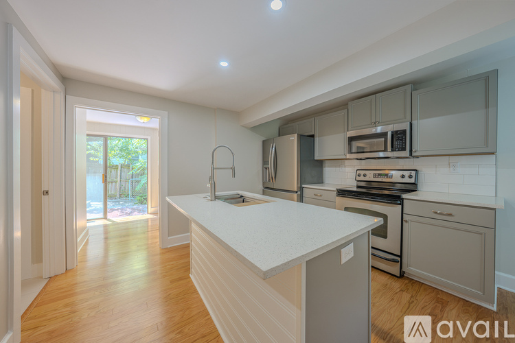 A kitchen with a white countertop and wooden flooring.