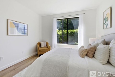 A bedroom with a large bed and a chair by the window.