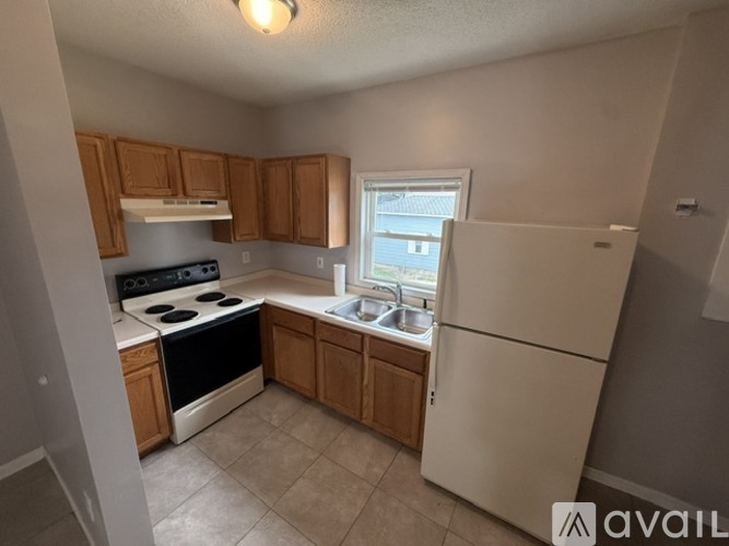 A kitchen with a white refrigerator, black stove, and wooden cabinets.