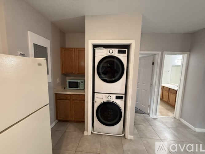 A white fridge is in a kitchen with a washer and dryer in the doorway.