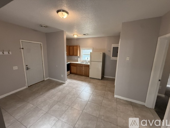 A spacious living room with a kitchen in the background.