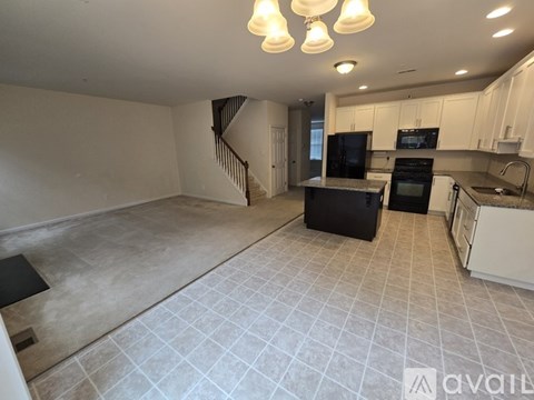 A kitchen with a black refrigerator and white cabinets.