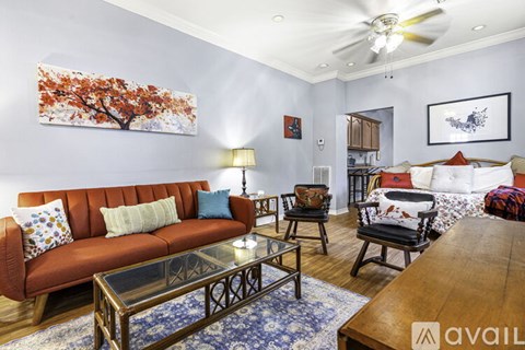 A living room with a red couch and a painting of a tree on the wall.