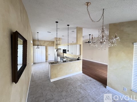 A spacious room with a kitchen island and a chandelier.