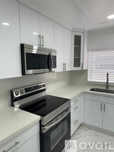 A modern kitchen with white cabinets and stainless steel appliances.