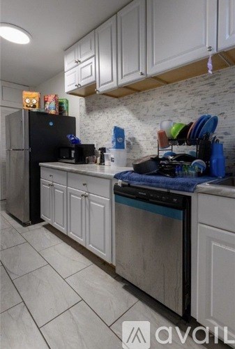 A kitchen with white cabinets and a black fridge.