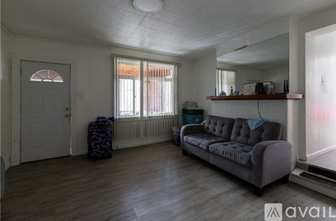 A living room with a grey couch and a wooden floor.
