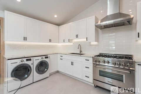 A modern kitchen with white cabinets and stainless steel appliances.