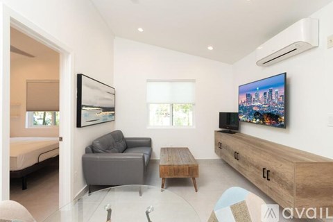 A modern living room with a grey sofa, a wooden coffee table, and a large painting on the wall.