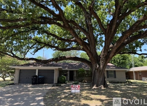A house with a tree in front and a for sale sign.