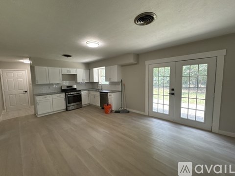 A spacious kitchen with white cabinets and a wooden floor.