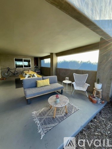 A living room with a grey couch, a white chair, and a small table with a plant on it.