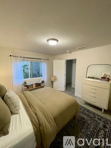 A bedroom with a bed, dresser, and window.