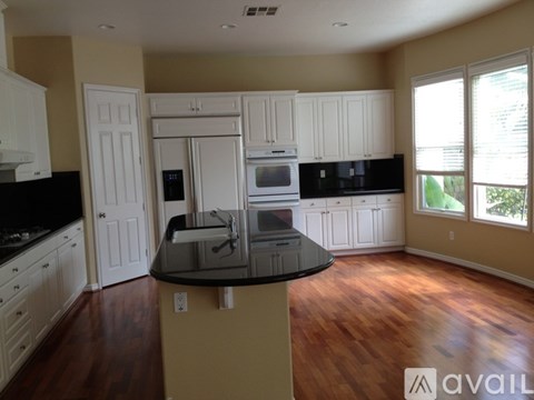A kitchen with white cabinets and black countertops.
