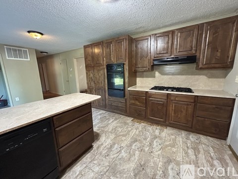 A kitchen with brown cabinets and a black dishwasher.