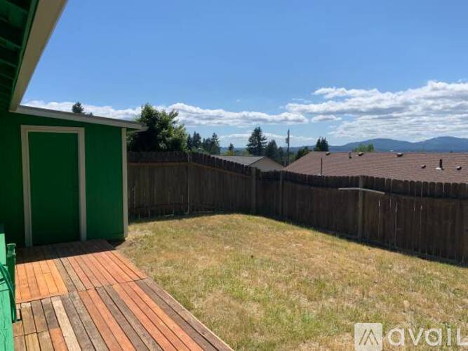 A backyard with a wooden deck and a green shed.