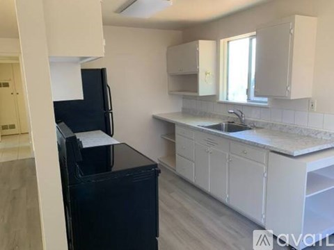 A kitchen with white cabinets and a black fridge.