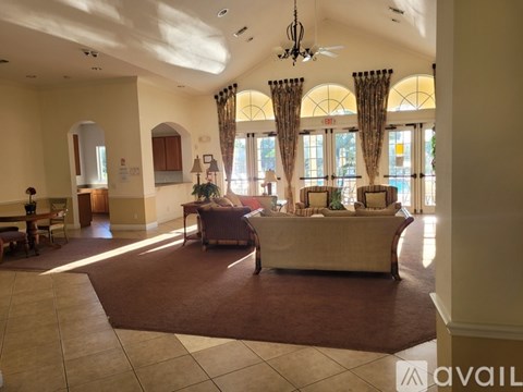 A spacious living room with a large couch and a chandelier.