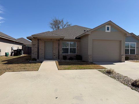 A house with a grey garage door and a brown roof.