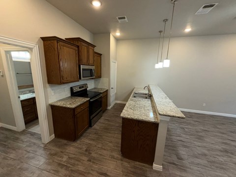 A kitchen with brown cabinets and a granite countertop.