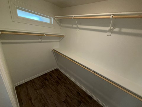 A small closet with a window and a wooden floor.