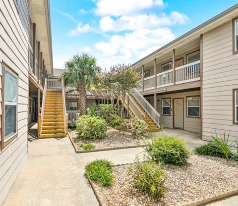 A sunny day at a residential complex with a well-maintained garden in the foreground.