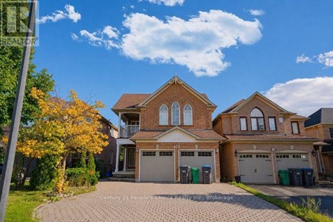 A large house with a brick facade and a driveway in front.