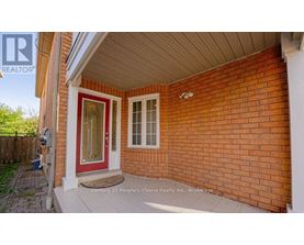A red door is on the left side of a brick house.