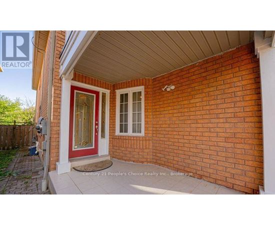 A red door is on the left side of a brick house.