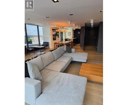 A living room with a large grey sofa and a wooden floor.