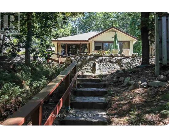 A house is situated in a wooded area with a staircase leading up to it.