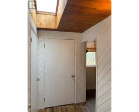 A white door in a room with wooden walls and ceiling.
