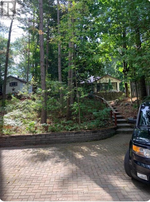 A black car is parked on a brick driveway.