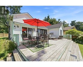 A wooden deck with a table and chairs is in front of a house.