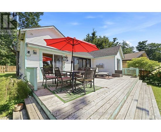 A wooden deck with a table and chairs is in front of a house.