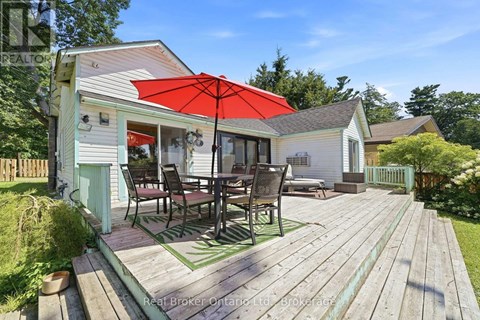 A wooden deck with a table and chairs is in front of a house.