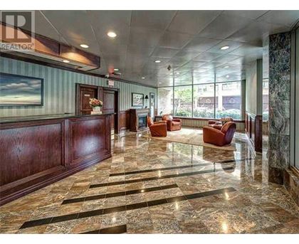 A spacious lobby with marble floors and wooden paneling.