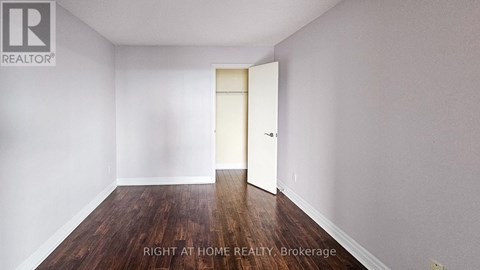 A room with a wooden floor and white walls, with a door on the right side.