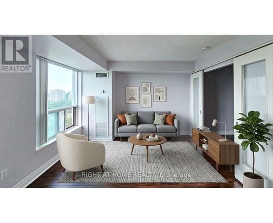 A living room with a grey couch, a white chair, a wooden coffee table, and a plant.