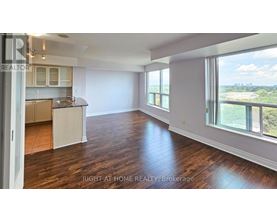 A spacious room with wooden floors and a large window overlooking a landscape.