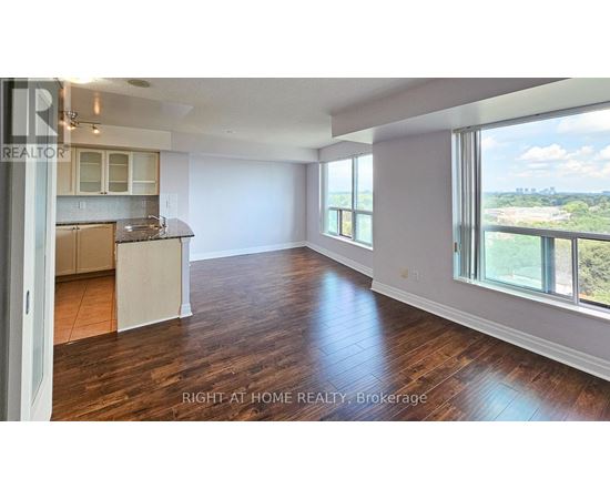 A spacious room with wooden floors and a large window overlooking a landscape.