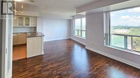 A spacious room with wooden floors and a large window overlooking a landscape.